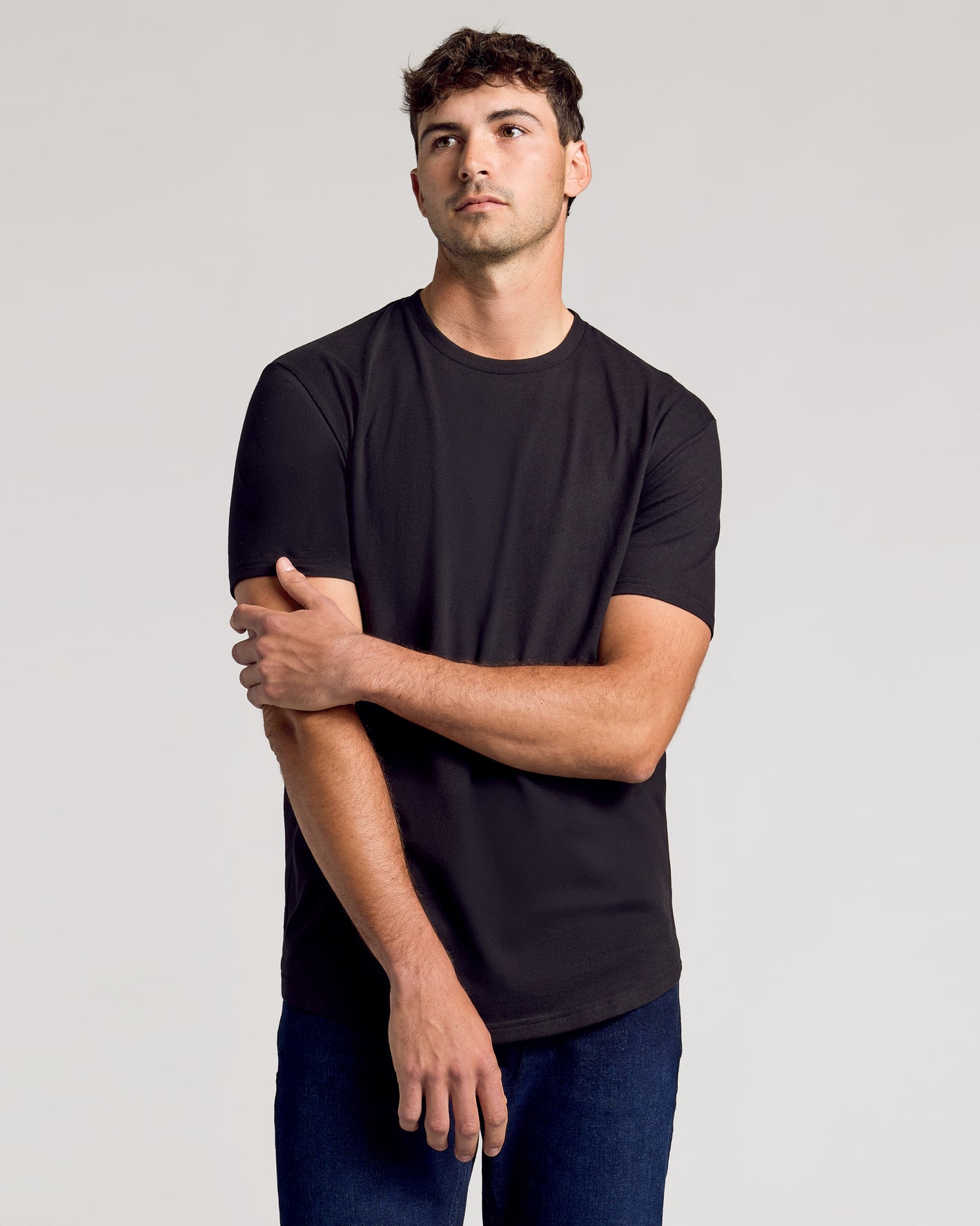 Young man modeling All Black Short Sleeve Tall Curved Hem Crew.