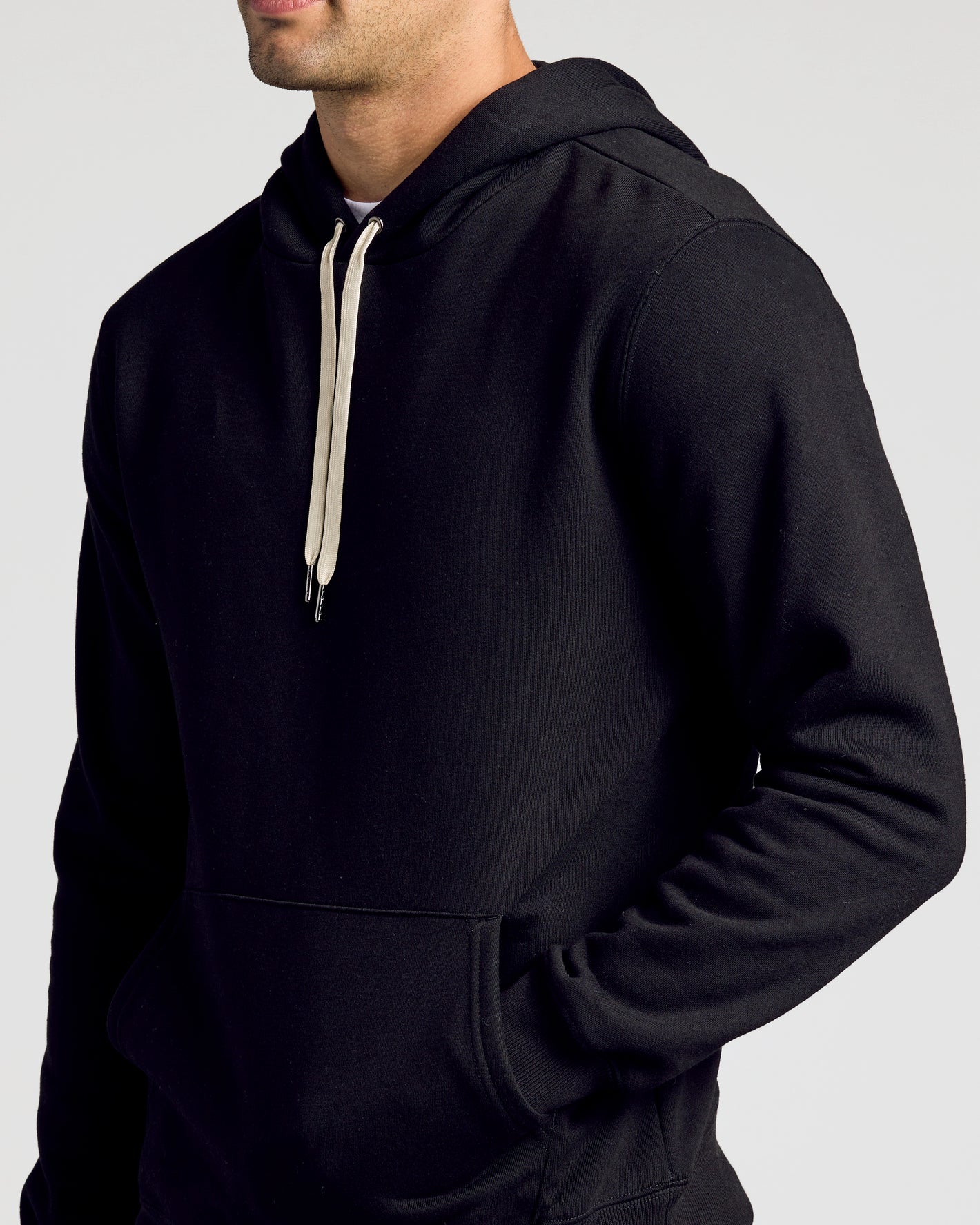 Person wearing a black hoodie with a white drawstring on a light gray background