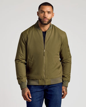 Man wearing Army Green Bomber Jacket with zip pocket and blue jeans.