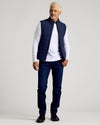 Man wearing Navy Puffer Vest, white shirt, and jeans.