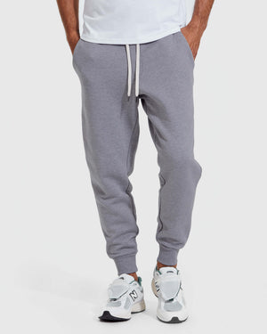 Front view of a person wearing Heather Gray Fleece French Terry Joggers with a white drawstring, paired with white athletic sneakers, showcasing a casual men's basics style.