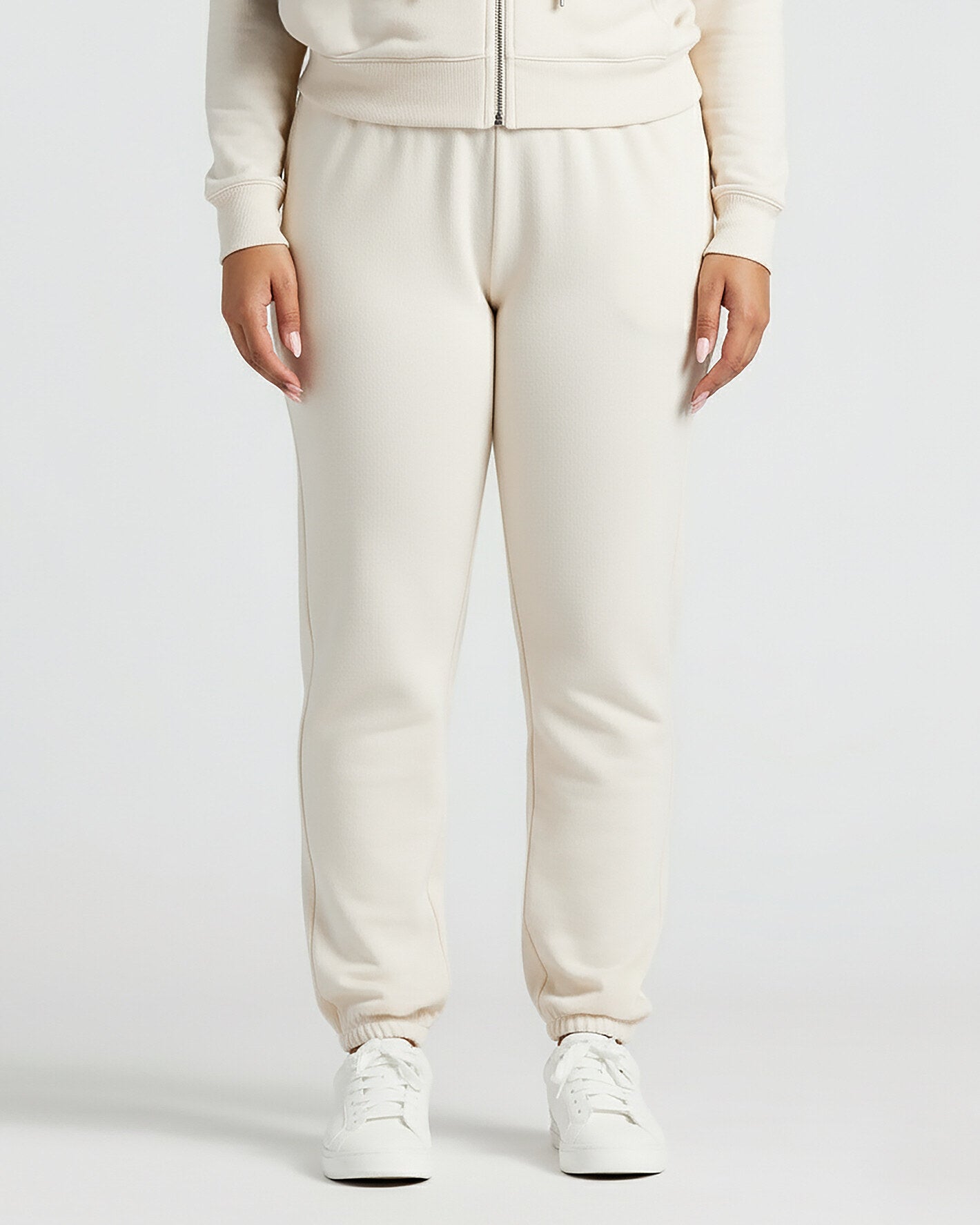 Womens Oatmeal Relaxed Joggers with elastic cuffs and white sneakers.