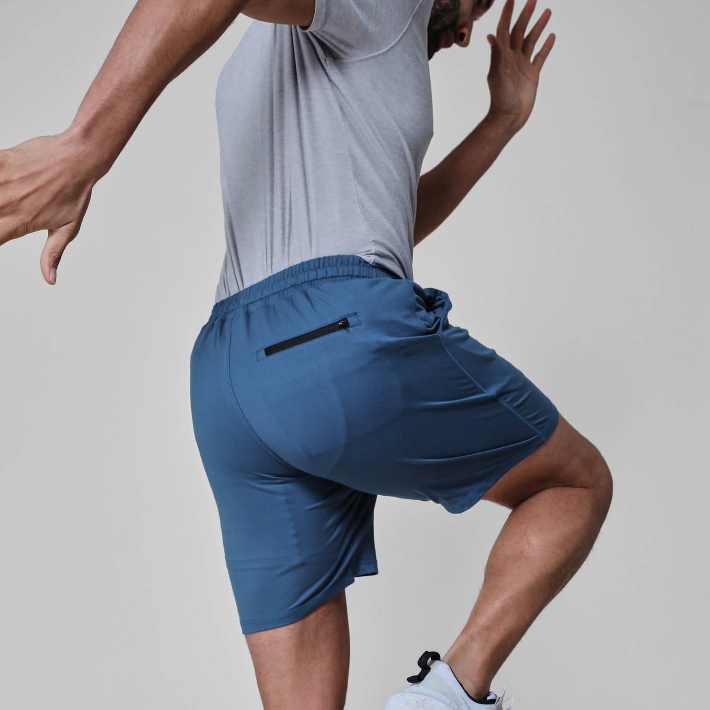 Man wearing Stone Blue Active Comfort Shorts, showcasing zip pocket and athletic movement.