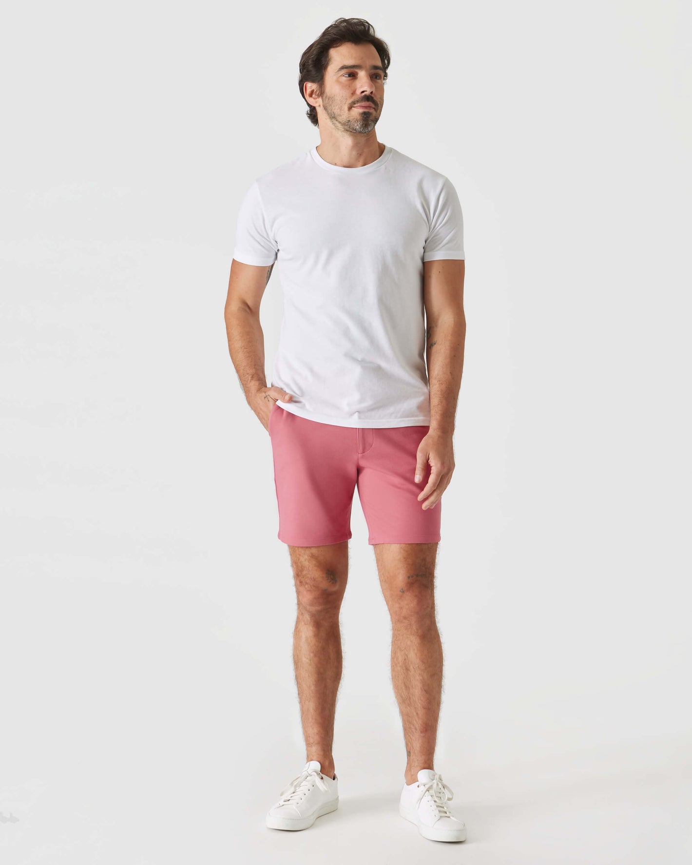 Man wearing 7 Rosewood Comfort Knit Chino Shorts, white T-shirt, sneakers.