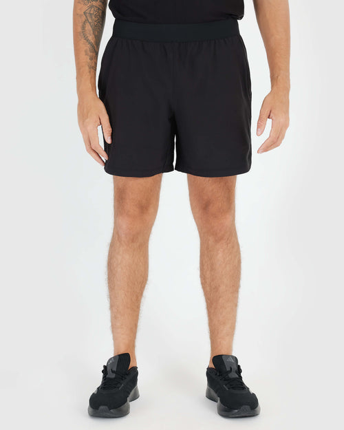 7 Black Active Training Short with tattooed arm and zippered pocket visible.