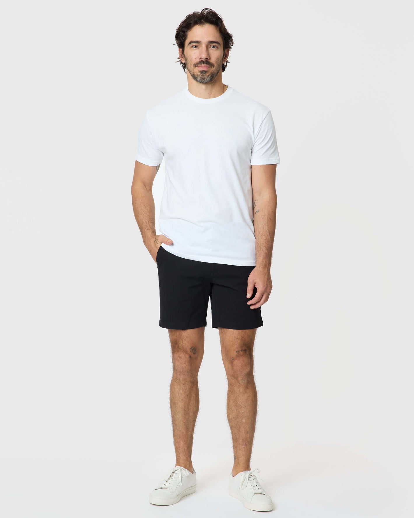 Man wearing 7 Black Classic Twill Shorts, white t-shirt, sneakers.