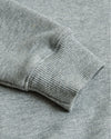 Close-up of a gray sweater sleeve on a matching fabric background
