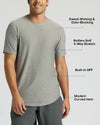 A man wearing a light gray heather short-sleeve athletic t-shirt with text callouts highlighting features like sweat-wicking, odor-blocking, 4-way stretch, built-in SPF, and curved hem.