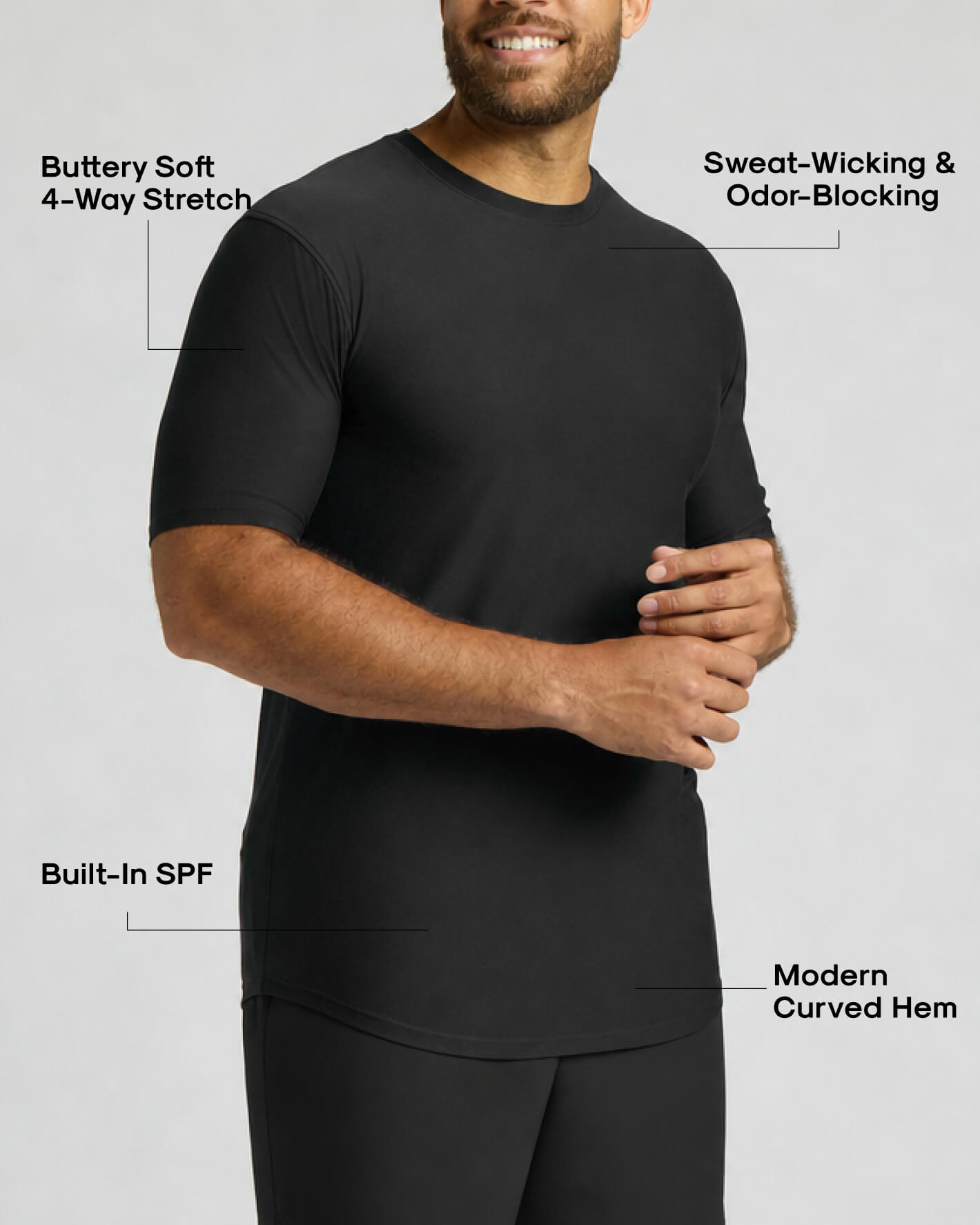 A man wearing a black short-sleeve athletic shirt with text callouts highlighting features such as buttery soft 4-way stretch, sweat-wicking and odor-blocking, built-in SPF, and modern curved hem.