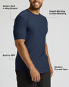 A man wearing a navy blue short-sleeve athletic t-shirt, shown from the chest down against a light gray background, with text callouts highlighting features like 4-way stretch, sweat-wicking, built-in SPF, and modern curved hem.