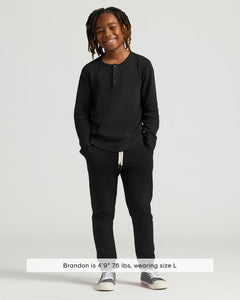 True ClassicBoy wearing Boys' Waffle Long Sleeve Henley 6-Pack, smiling with hands in pockets.