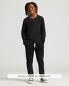 Boy wearing Boys' Waffle Long Sleeve Henley 6-Pack, smiling with hands in pockets.
