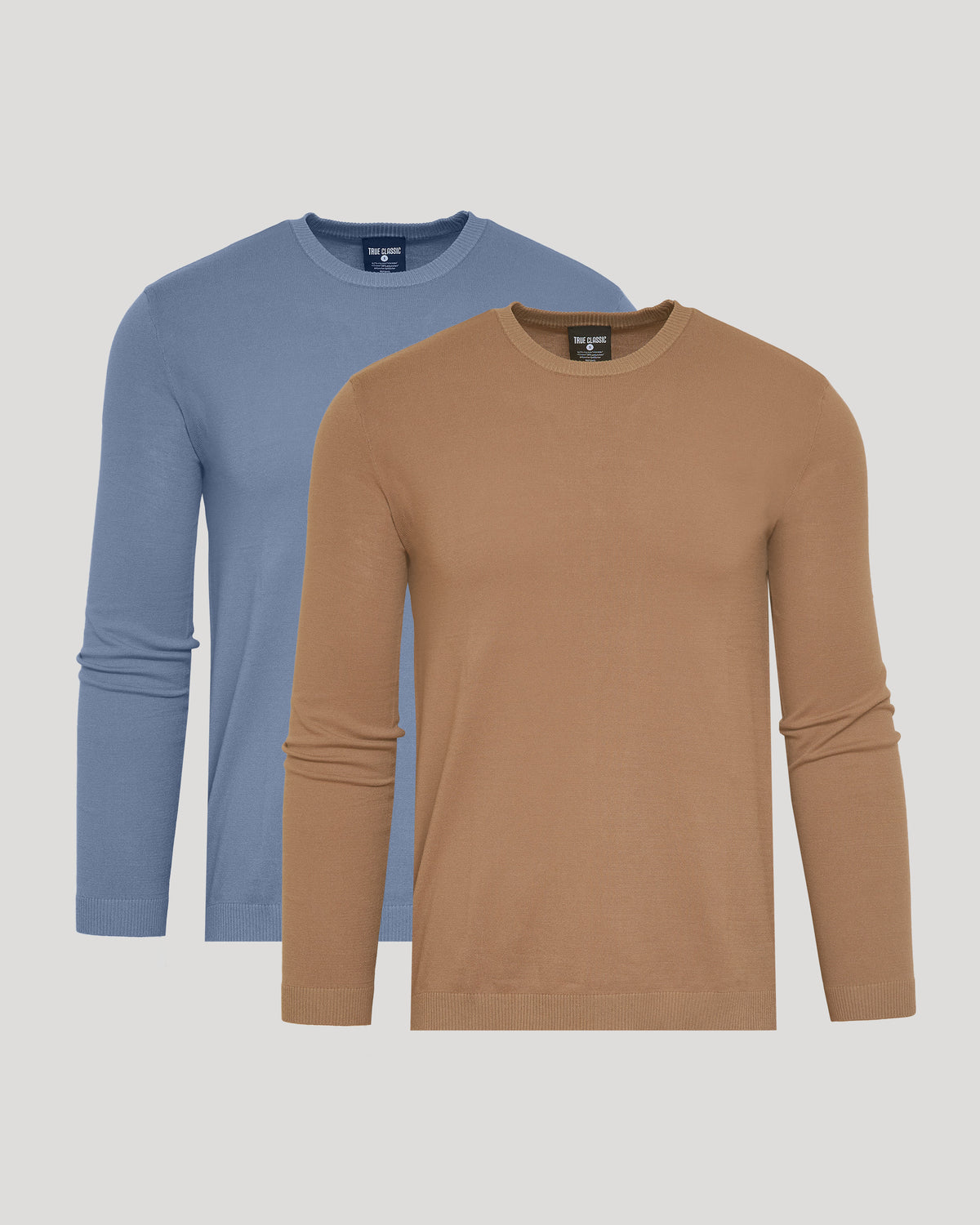 Two long-sleeve crew-neck knit shirts shown on a light gray background, with one in tan/camel in front and one in dusty blue behind.