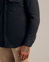 Black Fleece Shirt Jacket with chest flap pockets and tattooed hand visible.