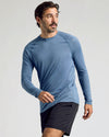 Man wearing Fiord Long Sleeve Active Mesh Crew, mid-stride, gazing sideways.