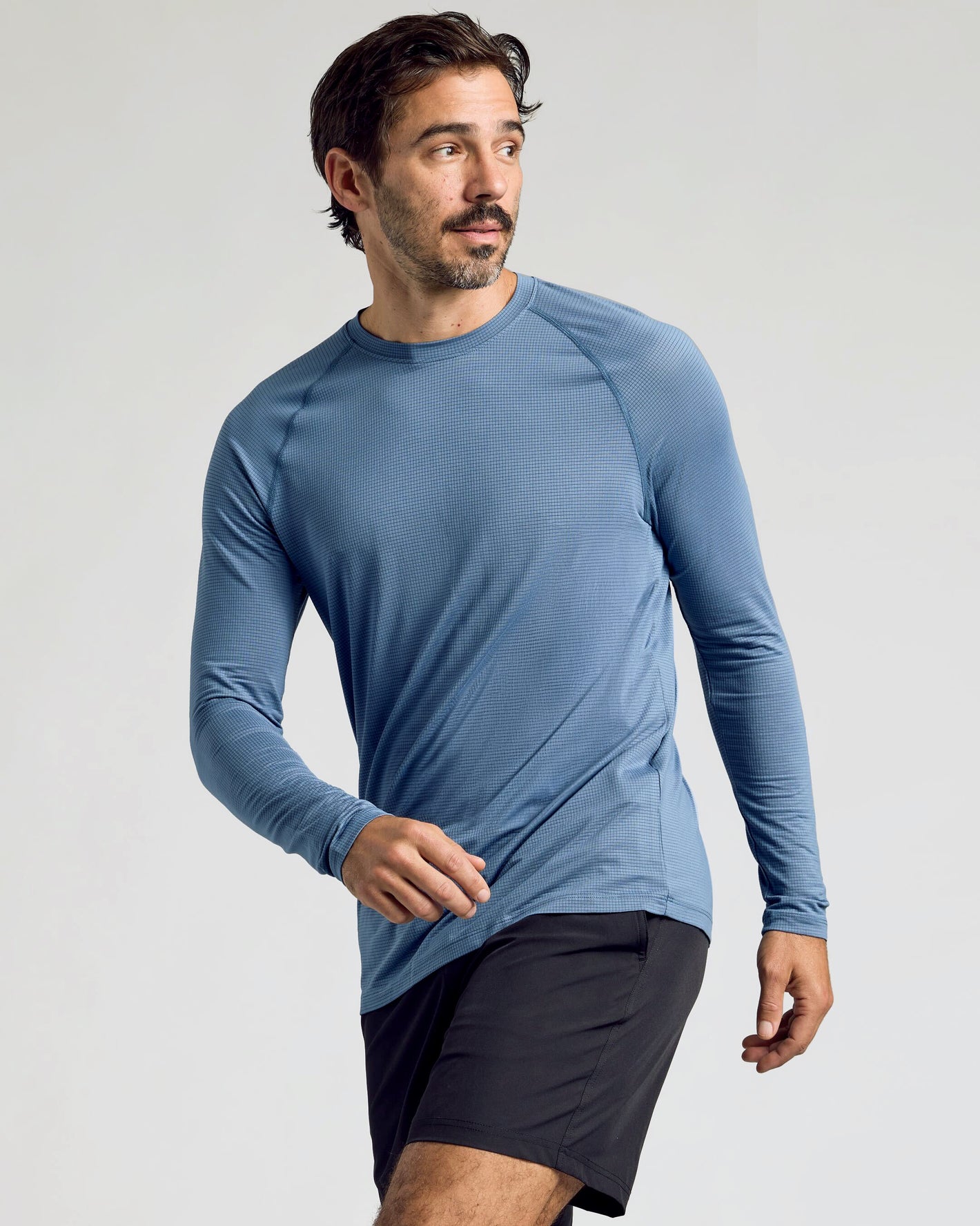 Man wearing Fiord Long Sleeve Active Mesh Crew, mid-stride, gazing sideways.