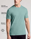 A man wearing a short-sleeve crew-neck t-shirt in a muted teal color, with text callouts on the left highlighting features like durability, arm fit, roominess in the torso, and silky smooth feel.