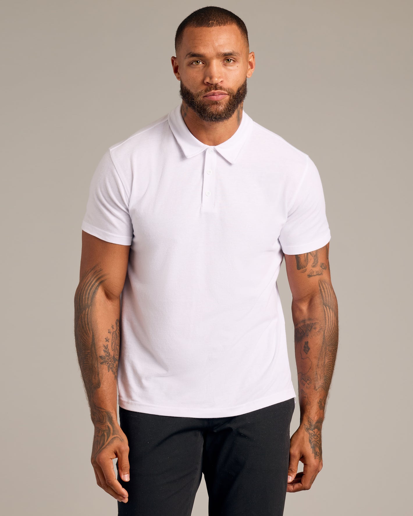 Man in Short Sleeve Variety 9-Pack: White Polo, tattooed forearms visible.