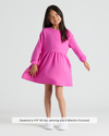 Girls Electric Fuchsia Long Sleeve Fleece Dress on young girl, white sneakers.