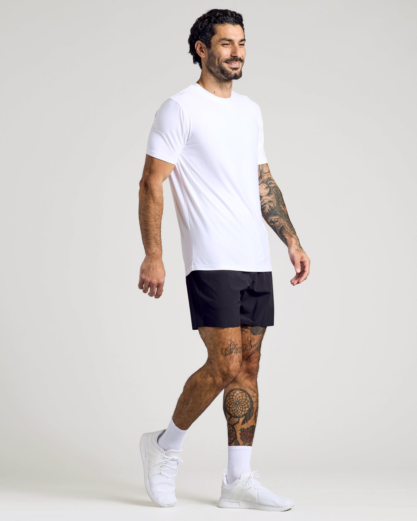 Man wearing White Active Crew Neck Tee, black shorts, white sneakers.