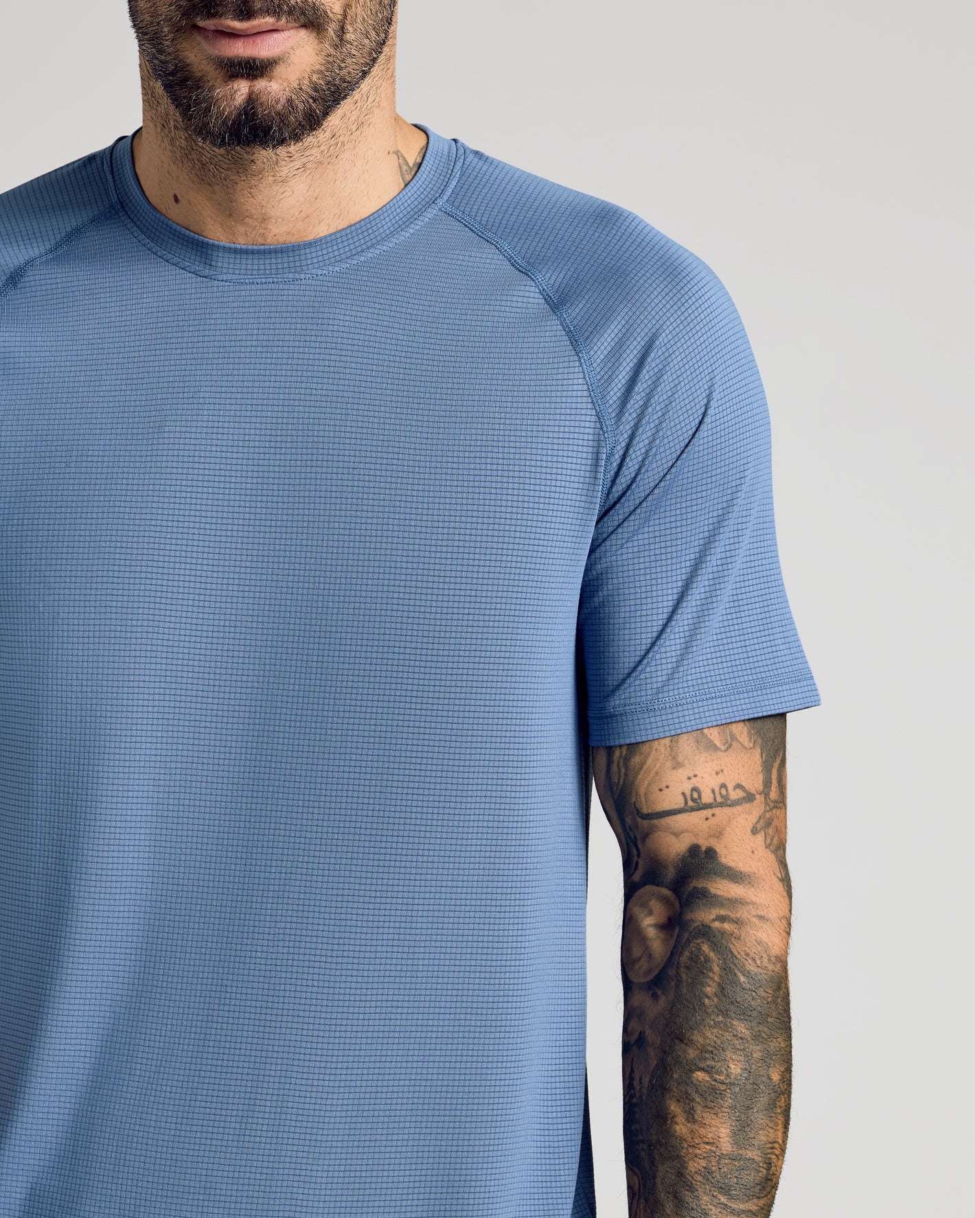 Fiord Active Mesh Crew on tattooed man, showcasing breathable, textured fabric.