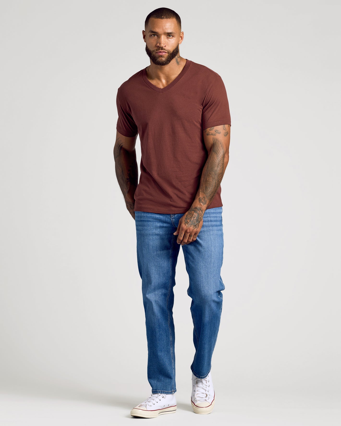 Dark Chocolate Classic V-Neck on male model, tattoos visible, with jeans and sneakers.