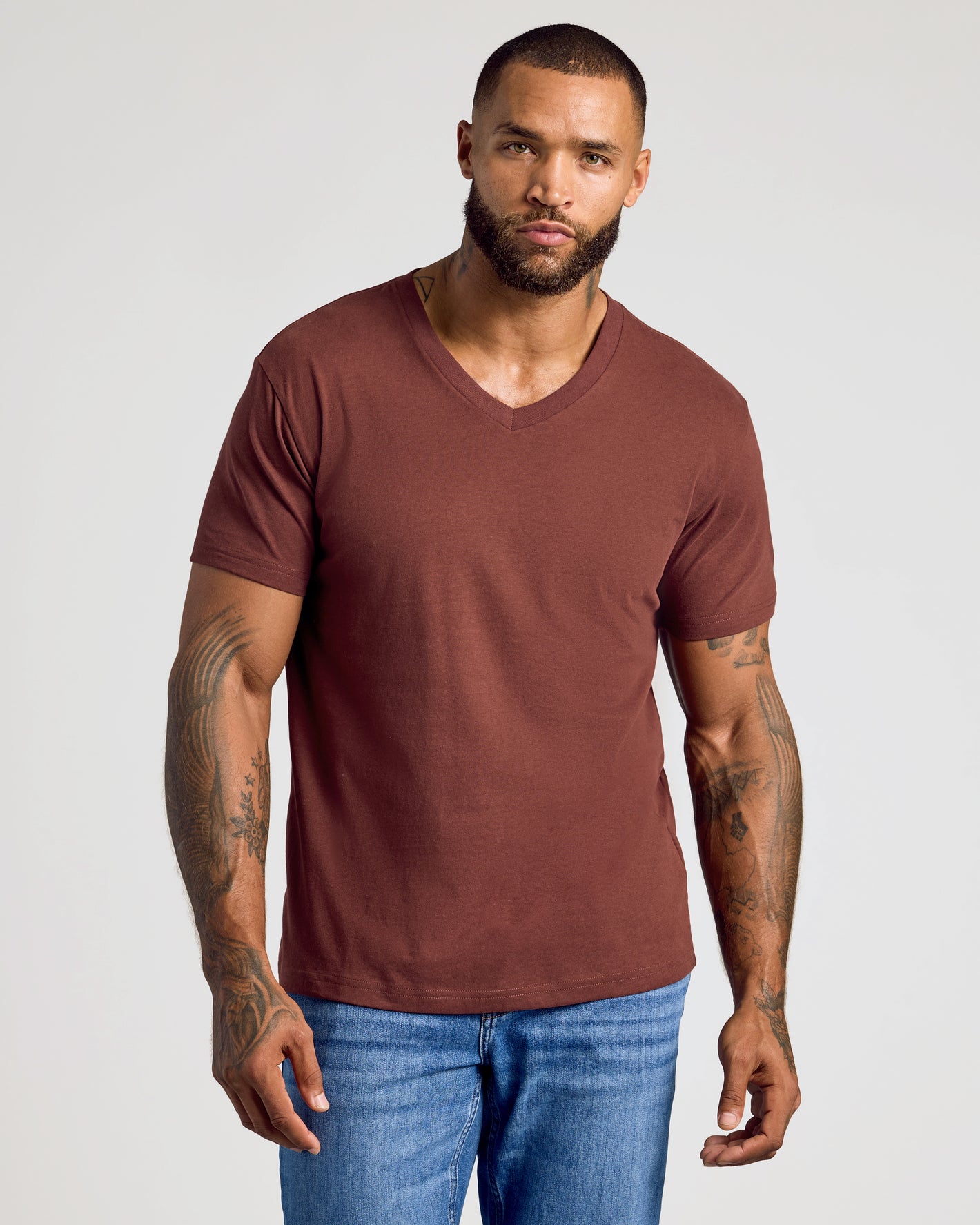 Male model in Dark Chocolate Classic V-Neck and jeans, showcasing tattoos.