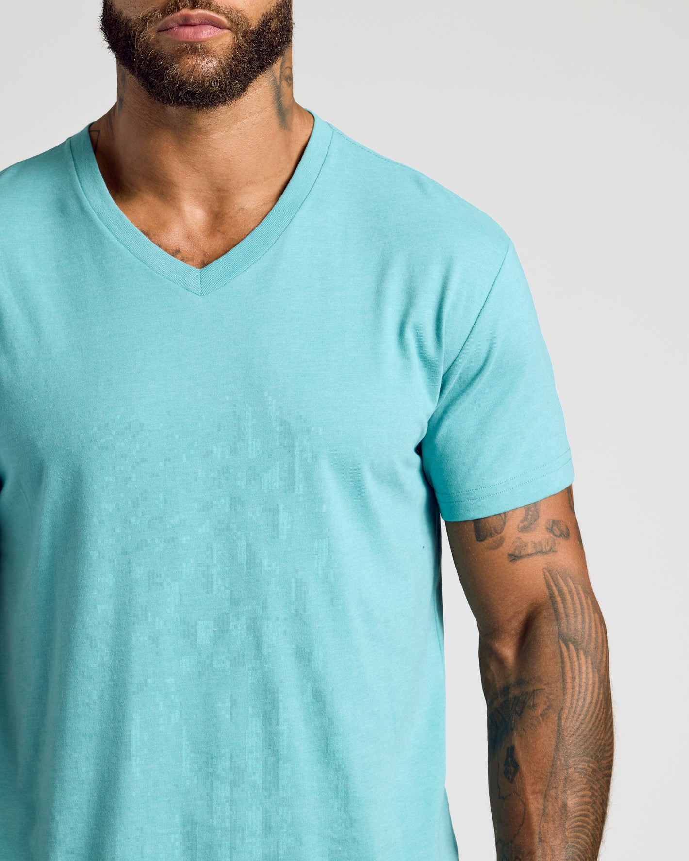 Man wearing Dark Heather Oceanic Classic V-Neck, showcasing tattoos on right arm.