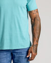 Dark Heather Oceanic Classic V-Neck showcased on tattooed arm, medium-wash jeans.