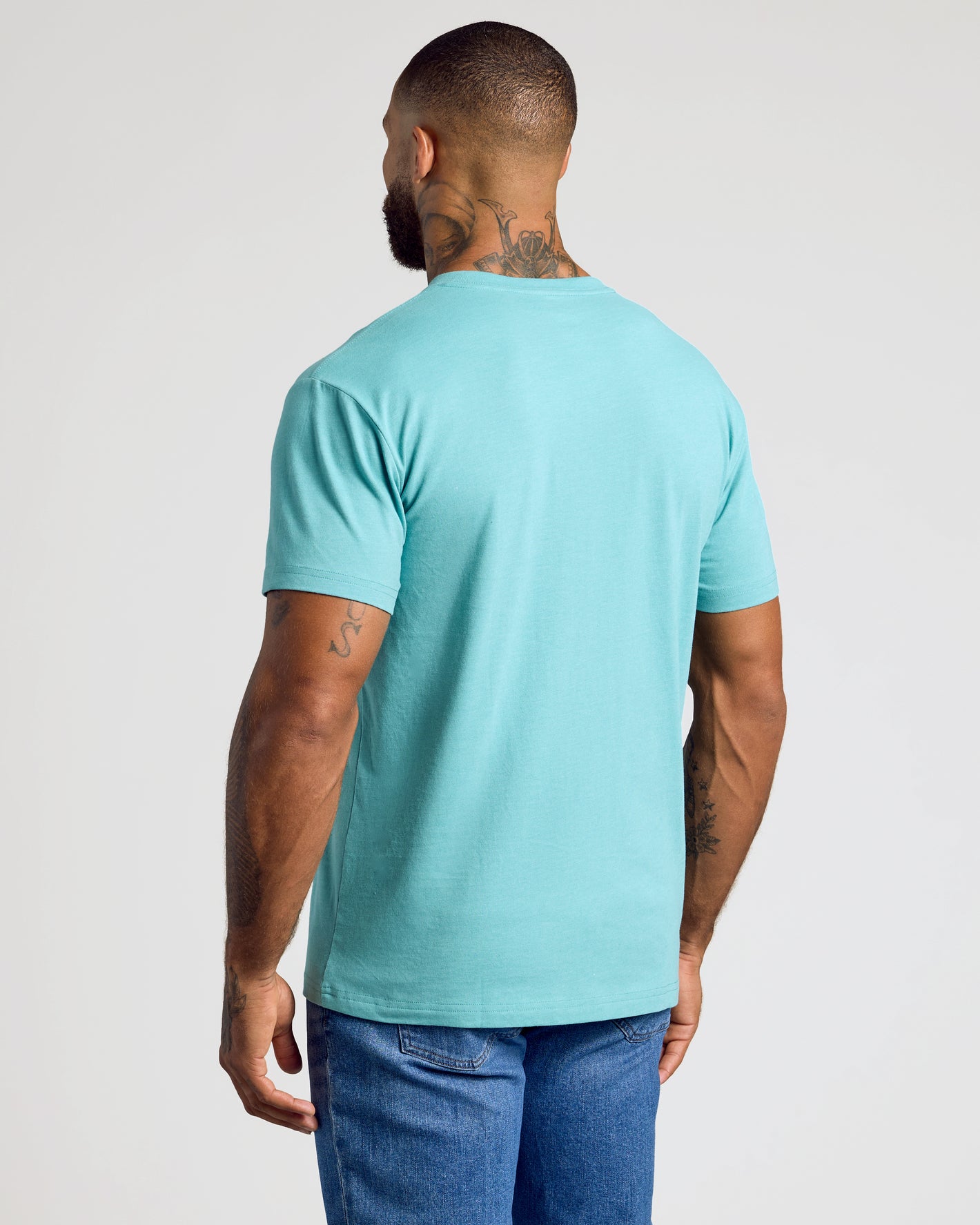 Man in Dark Heather Oceanic Classic V-Neck, showcasing tattoos and athletic fit.