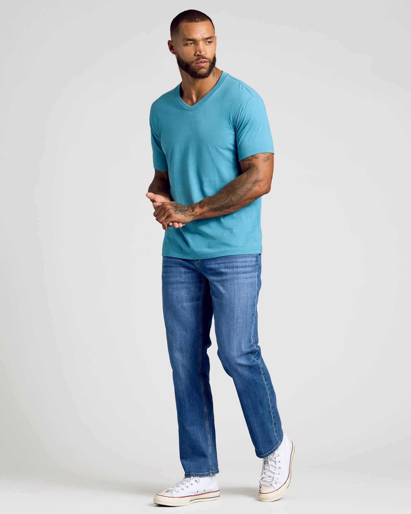Model wearing Dark Heather Harbor Classic V-Neck, showcasing tattoos and relaxed style.