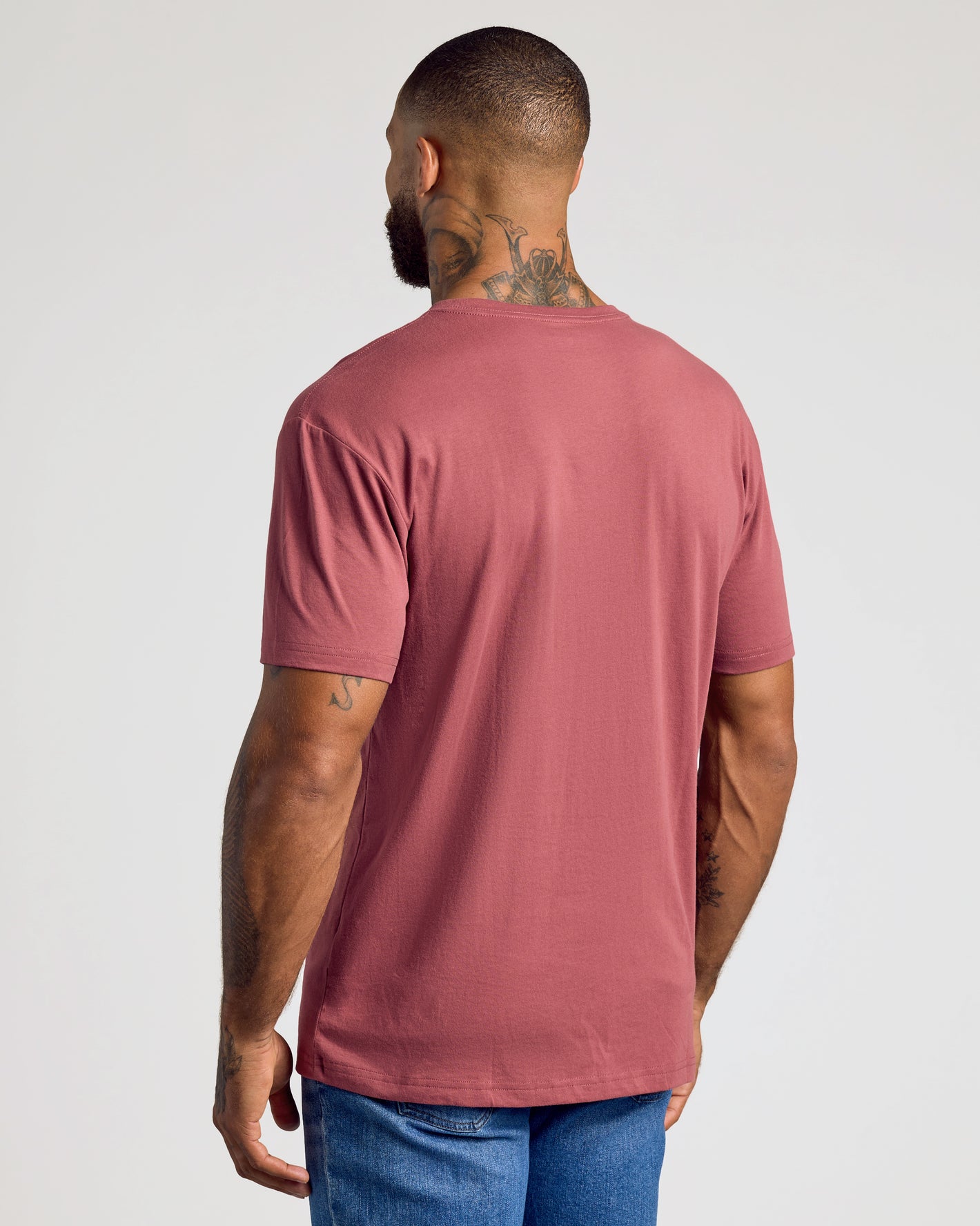 Man wearing Rustic Apple Classic V-Neck and blue jeans, back view.