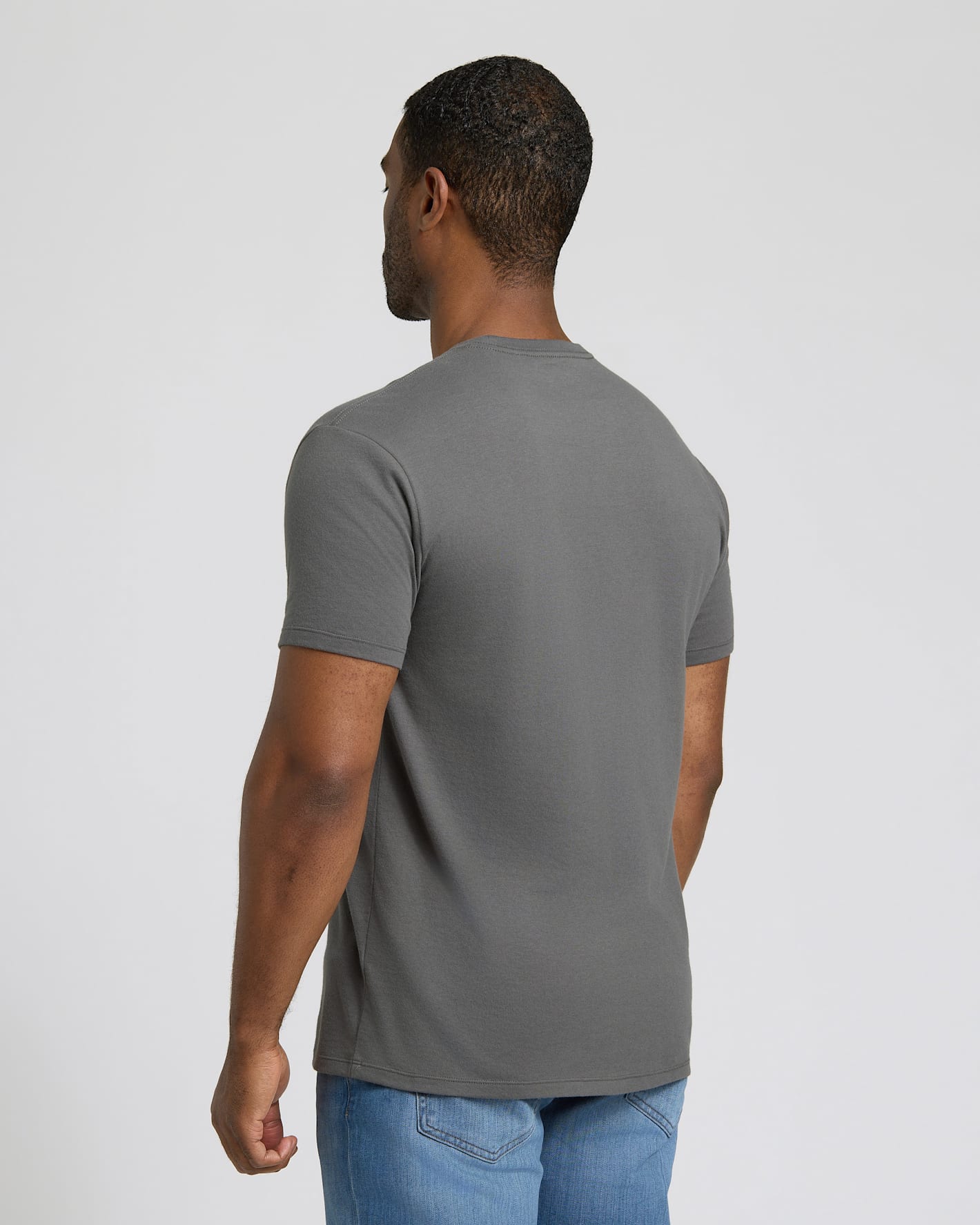 Man wearing a charcoal gray Short Classic Crew Neck 3-Pack t-shirt, shown from the back, paired with light blue jeans, displaying a comfortable fit and classic style for men's basics.