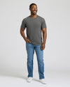 Man wearing a gray t-shirt and blue jeans standing against a plain background. MODEL_INFO: Model is 5'8" wearing size M short