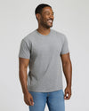 Man wearing a gray t-shirt and blue jeans against a plain background