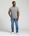 Man wearing a gray t-shirt and blue jeans standing against a plain background. MODEL_INFO: Model is 5'8" wearing size M short