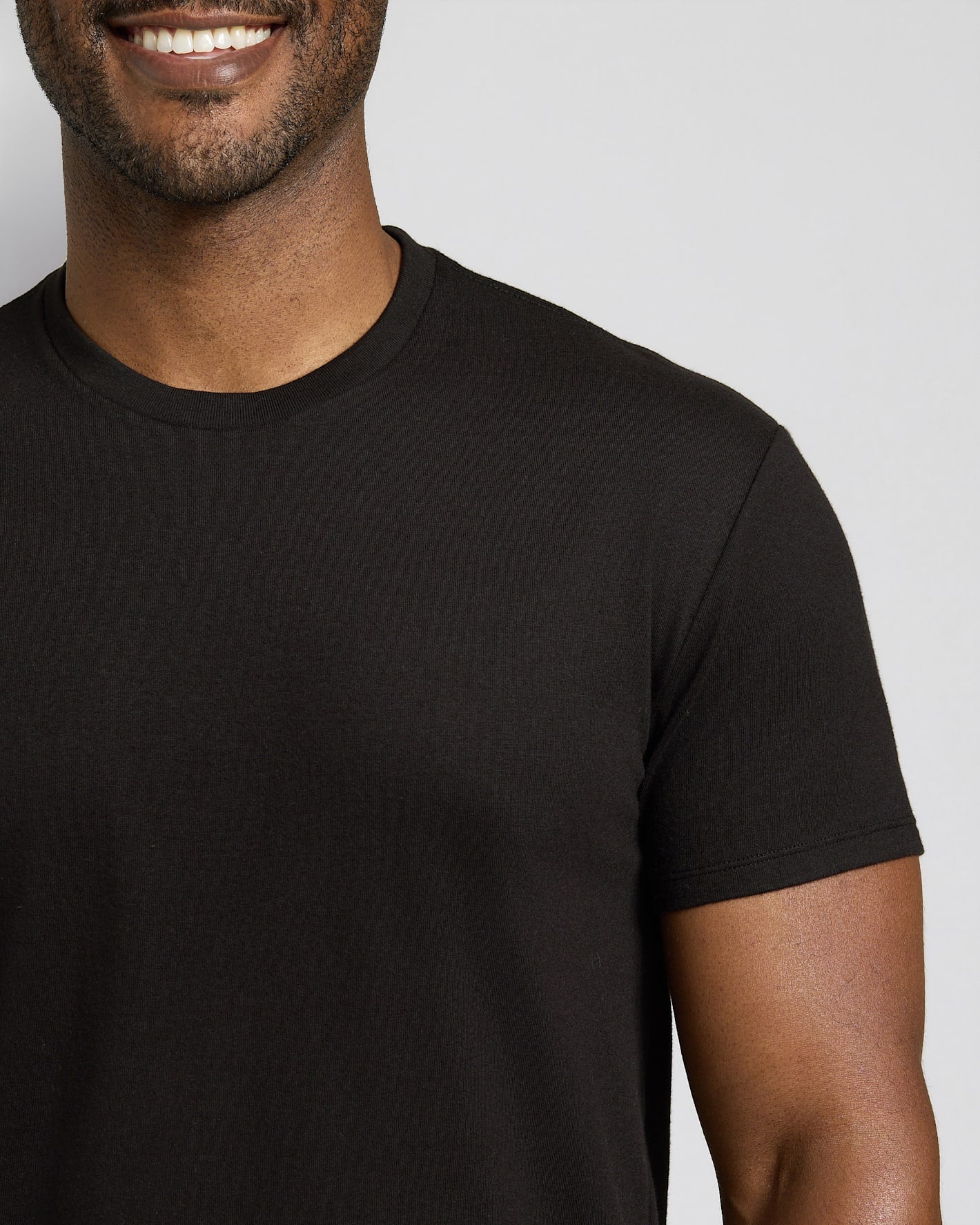 Smiling man wearing a black t-shirt against a plain background