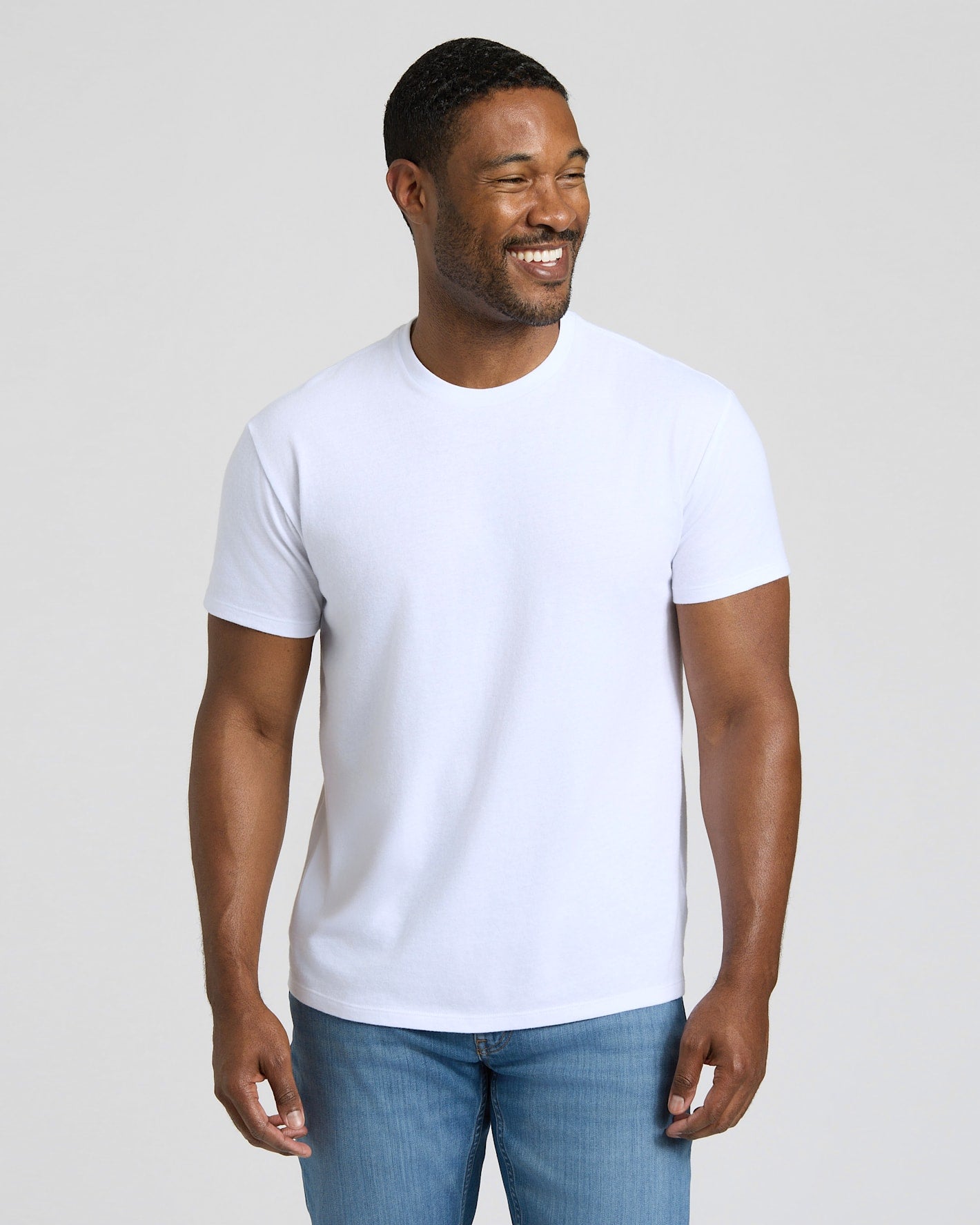 Man wearing a plain white t-shirt and blue jeans against a light background