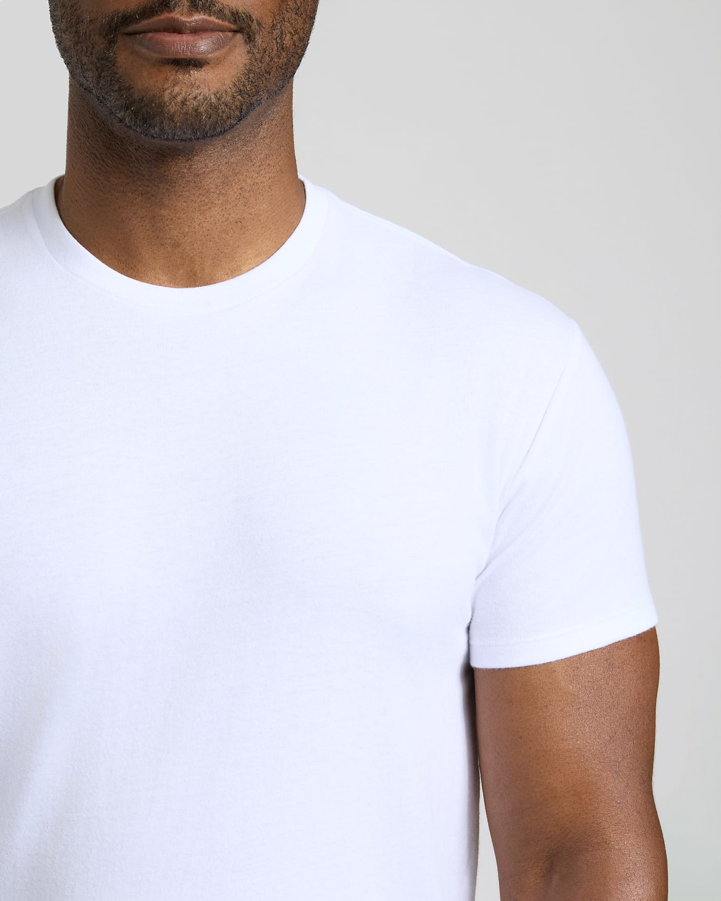 Man wearing a plain white t-shirt against a neutral background