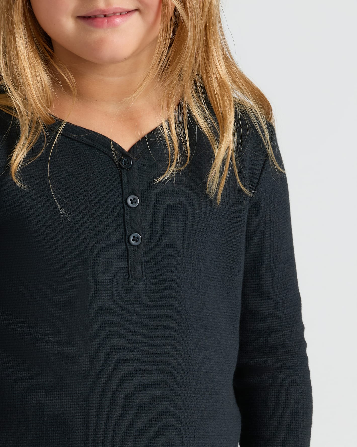 Child wearing Girls Black Waffle Long Sleeve Henley against plain background.