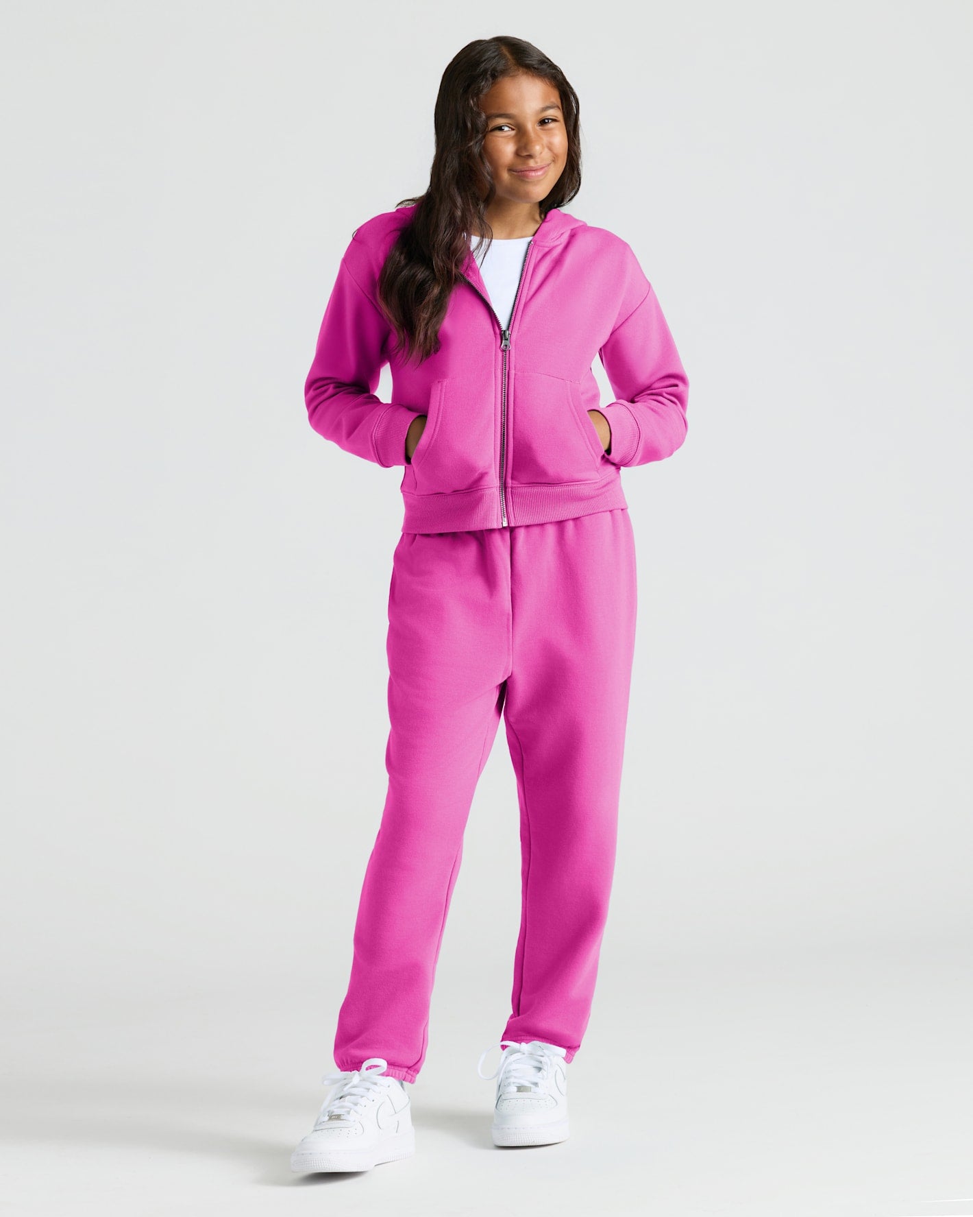 Girl in Electric Fuchsia hoodie and joggers from Girls Stormcloud & Electric Fuchsia Relaxed Joggers 2-Pack, smiling.
