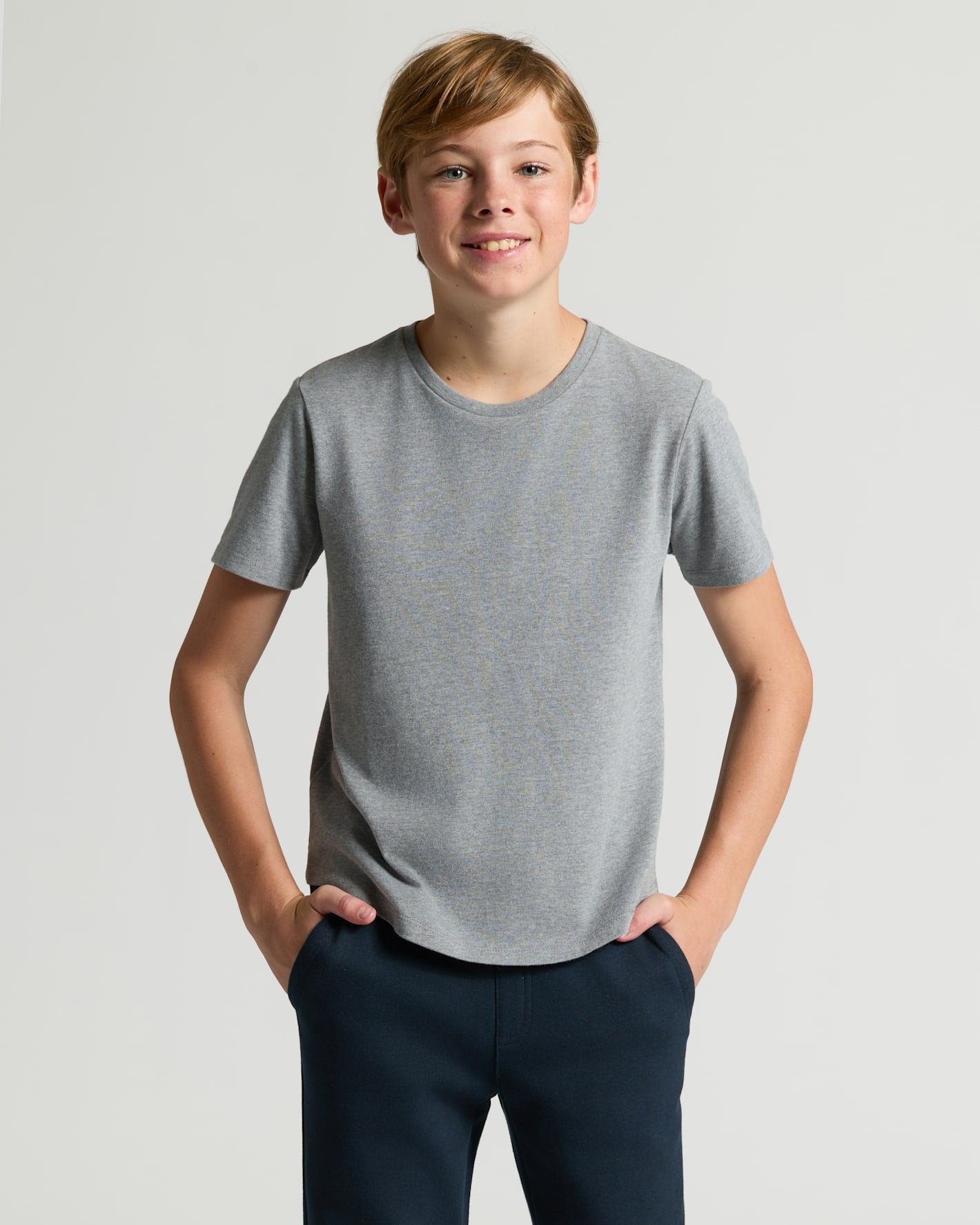 Boy wearing Boys' Classic Curved Hem Crew Neck T-shirt, hands in pockets.
