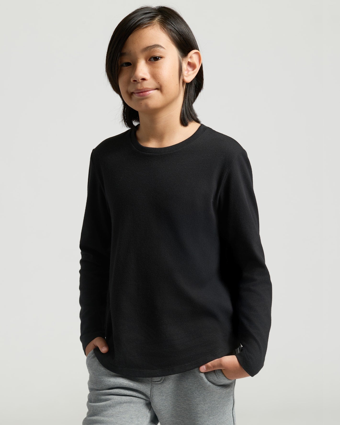 Young boy wearing Boys' All Black Classic Long Sleeve Curved Hem Crew Neck.
