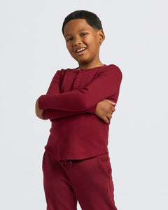 True ClassicBoy wearing Boys' Waffle Long Sleeve Henley, burgundy, smiling confidently.