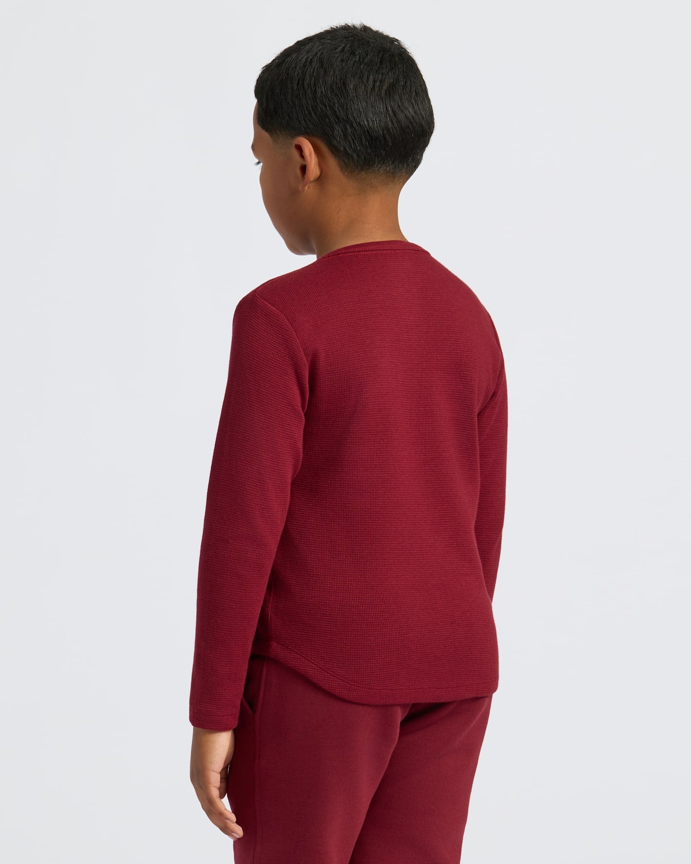 Boy wearing Boys' Waffle Long Sleeve Henley, maroon, side profile.