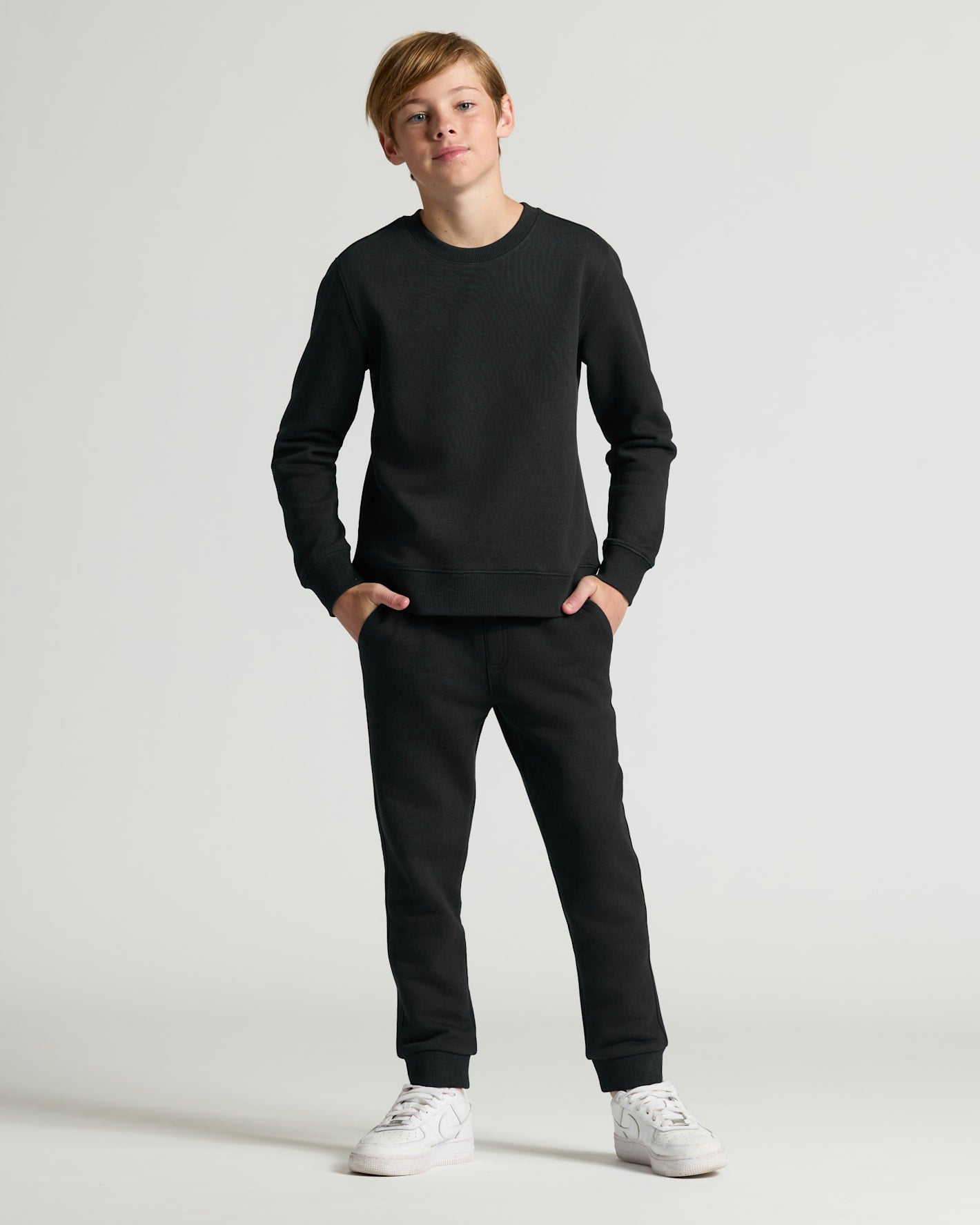 Person wearing a black long-sleeve shirt and black pants on a white background