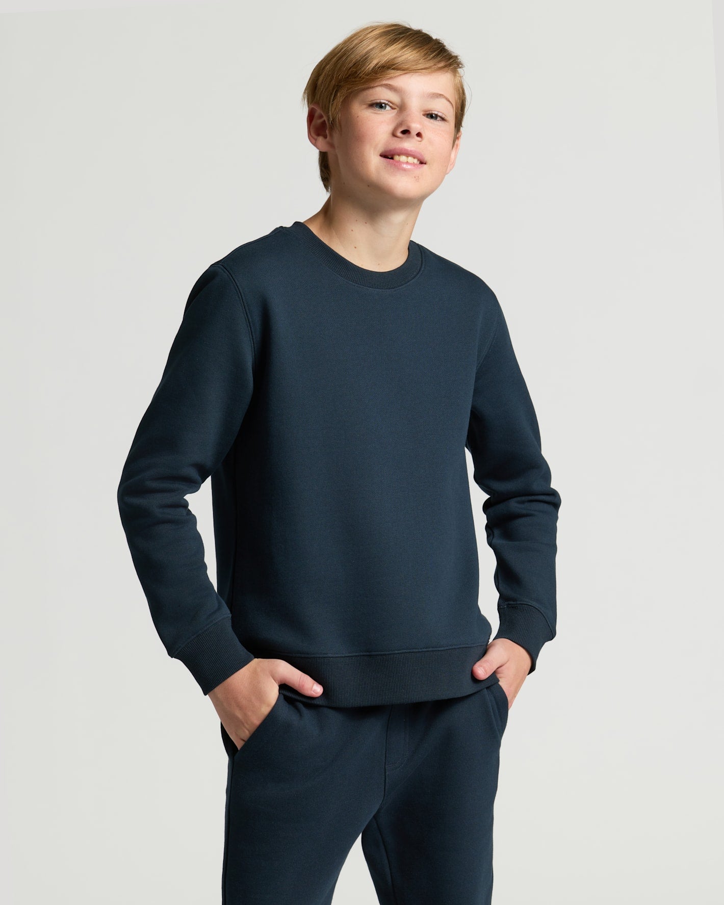 Child wearing a navy blue sweatshirt and pants on a light gray background