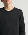 Person wearing a black sweater on a light gray background