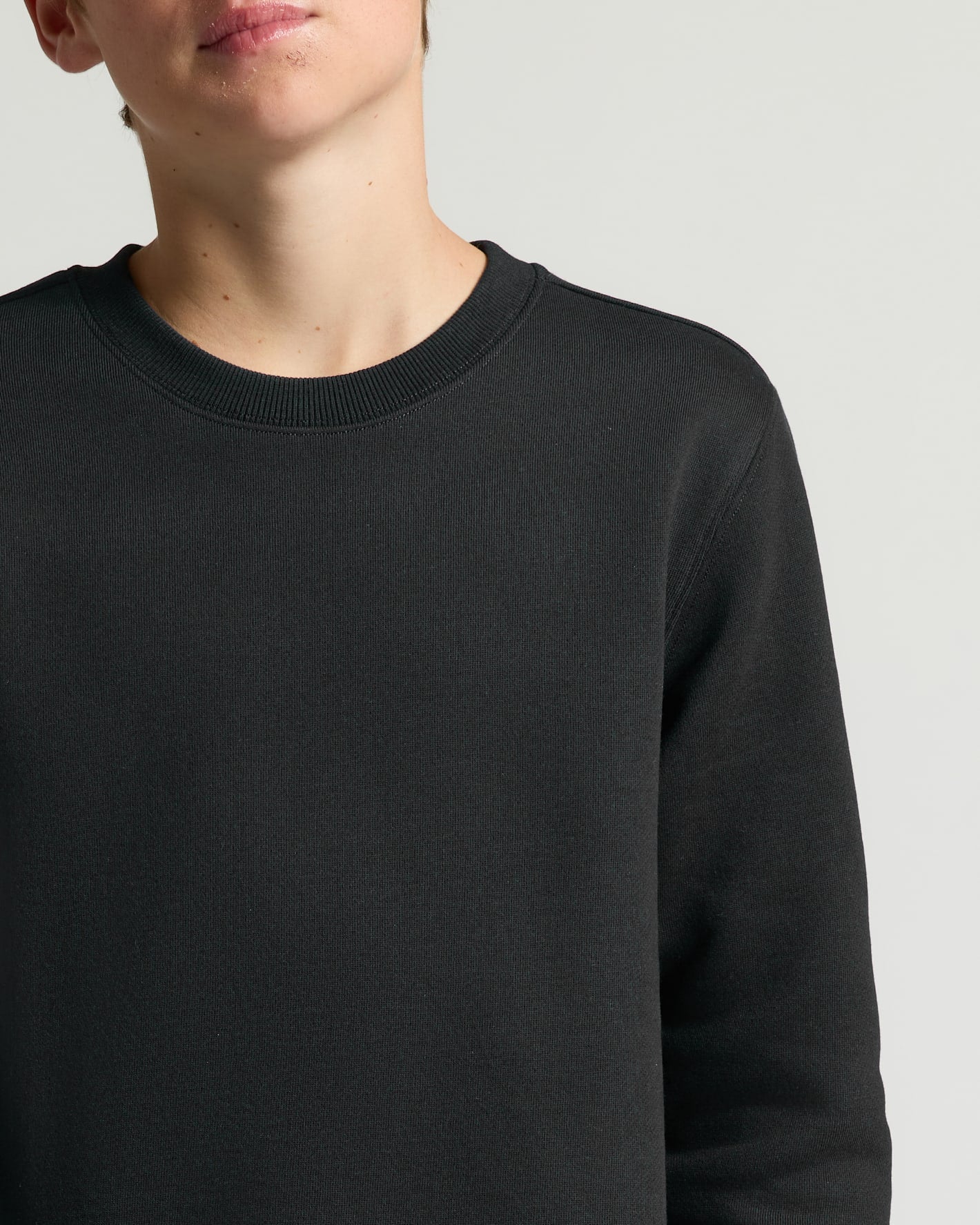 Person wearing a black sweater on a light gray background