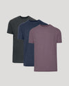 Three short-sleeve crew-neck t-shirts in dark gray, navy blue, and heathered dusty purple, arranged in a layered stack on a light gray background.